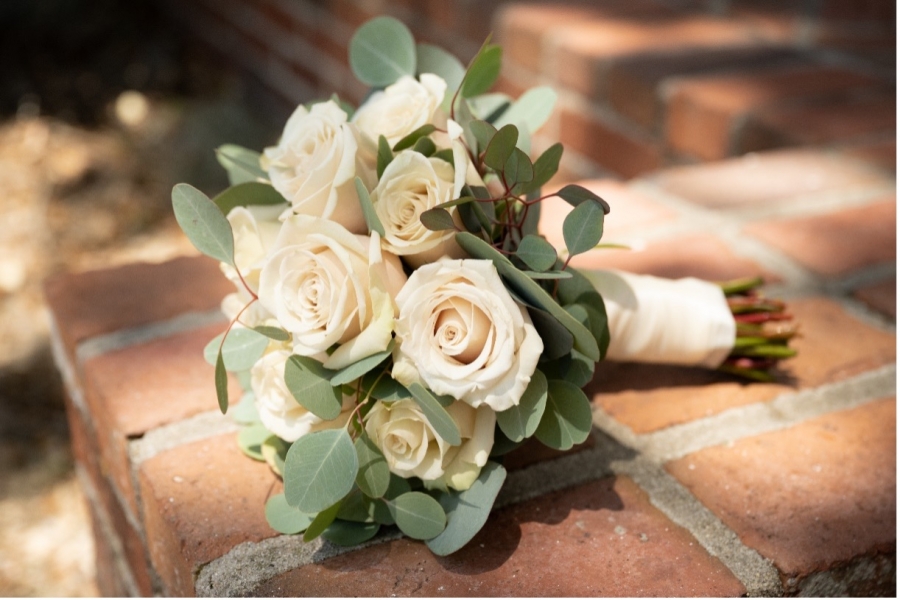 Bridal bouquet with white roses laying on brick walkway